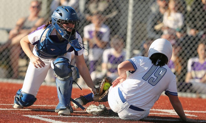 Olympic’s Emy Brant-Carrier (19) beats the tag of North Kitsap catcher Kendall Becker for a run at Lobe Fields on Tuesday, March 19, 2024.