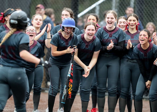 Kingston players cheer as they gather around home plate to celebrate the home run hit by Makynzee Riches (35) in Silverdale on Friday, March 22, 2024. Kingston won the game 13-8.